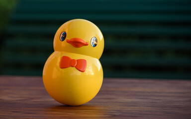 Vintage roly-poly toy shaped like a cute yellow chick. Tumbler toy isolated on an outdoor wooden...
