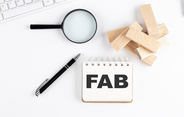 FAB - Feature Advantage Benefits word written on notebook with block magnifier and pen , business...