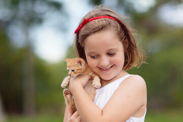 Little girl holding baby cat. Kids and pets