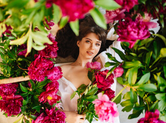 a beautiful and gentle young woman lies in peony flowers. feminine beauty. 
