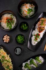 Various dishes of Asian cuisine with different types noodles and rice with shrimp, duck, vegetables and black sesame