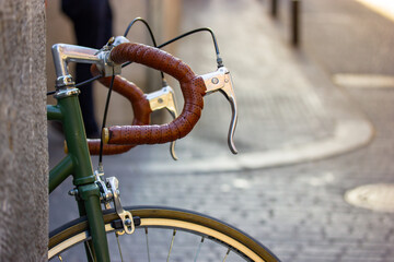 Green retro bike parked on a European city street. A vintage old classic bicycle handlebar and a...