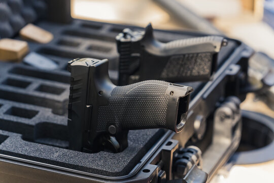 Two black handguns placed in special container case. No people. Outdoor closeup shot. Day at the shooting range. Firearm concept. High quality photo