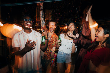A group of friends is celebrating with confetti at a nighttime rooftop party.