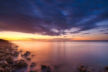 A seaside sunset during sunset. A long exposure photo. Landscape during a bright sundown. The sea and reflections on the water. - Powered by Adobe