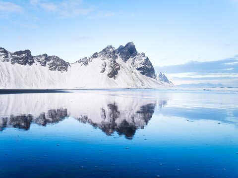 Stokksness, Vestrahorn National Park, Iceland. Wide beach with black volcanic sand. Reflections on the seashore at high tide. View of Iceland's nature in winter time.