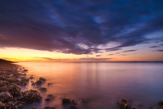A seaside sunset during sunset. A long exposure photo. Landscape during a bright sundown. The sea and reflections on the water.