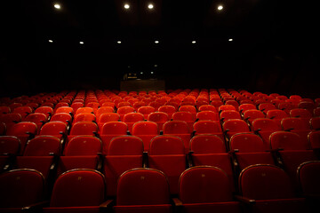 Empty theatre with red seats in low light stock photo