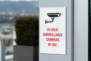 24 hour surveillance cameras in use security warning sign on blurred background