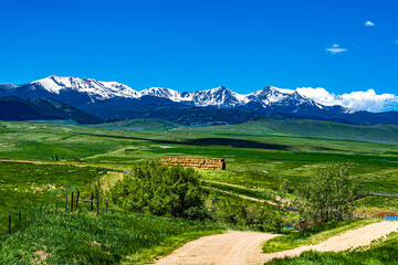 The farmland is surrounded by snow capped mountains in the Montana landscape