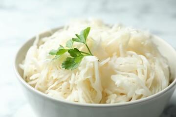 Tasty fermented cabbage with parsley on table, closeup