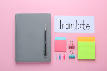 Paper with word Translate and stationery on pink background, flat lay