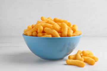 Many tasty cheesy corn puffs on white marble table