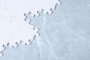 Blank white puzzle pieces on light grey marble background, flat lay. Space for text