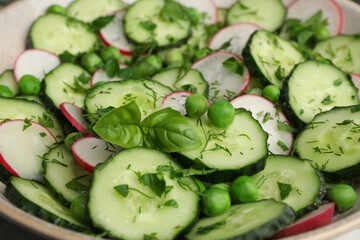 Appetizing salad with cucumbers, radish and pea in bowl, closeup