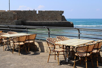 A chair in a city park on the seashore.