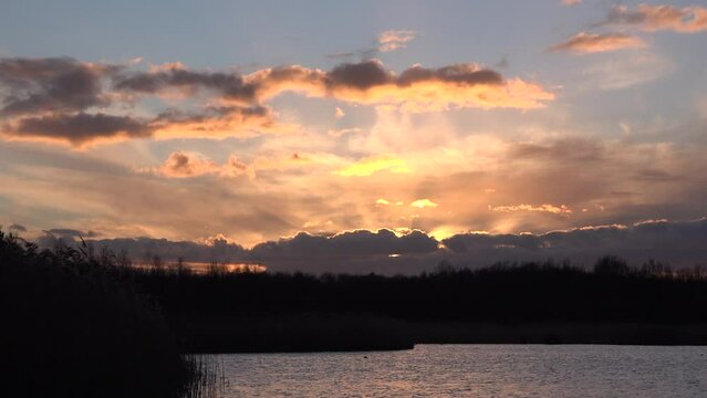 Sunset over lake as serine scene in England relaxes and calms the mind. Golden light water and reeds UK 4K