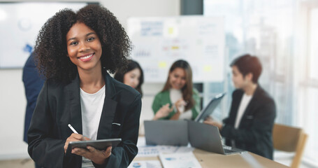 Attractive young confident businesswoman standing in office with digital tablet