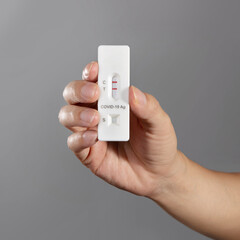 Man holding Rapid Antigen Test kit with Positive result during swab COVID-19 testing. Coronavirus...