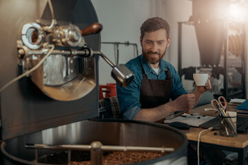 Business owner of coffee roasting factory working and drinking coffee