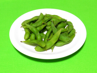白い皿の上の枝豆を緑背景で撮影した。