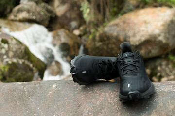 zapatos deportivos  de color negro con un rio de fondo