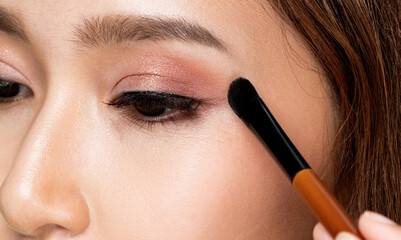 Closeup ardent young woman with healthy fair skin applying her eyeshadow with brush. Female model with fashion makeup. Beauty and makeup concept. - obrazy, fototapety, plakaty