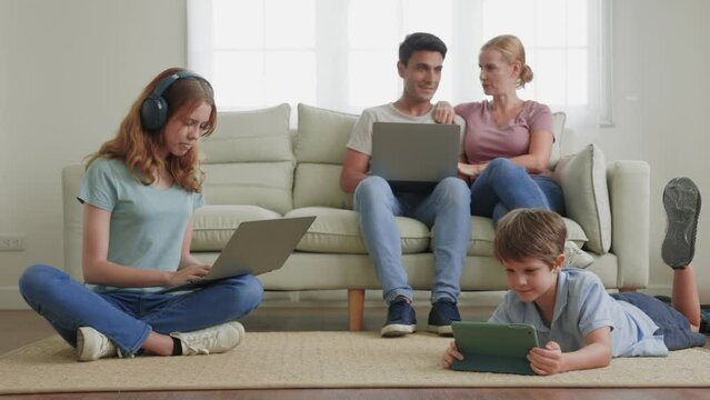 A parent and Children using a laptop, smartphone in the living room.