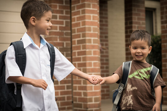 6 year old mixed race boy leaves home with his preschooler brother for his first day of school