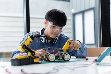 Asian teenager doing robot project in science classroom.