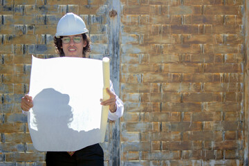 Elegant young engineer - architect working with his blueprints in hand while supervising a...