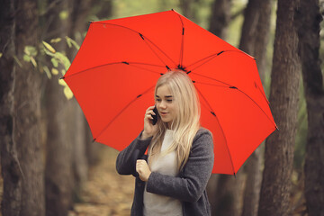 girl with umbrella posing in autumn park, october landscape lonely woman holding a red umbrella