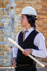 Elegant young engineer - architect working with his blueprints in hand while supervising a...