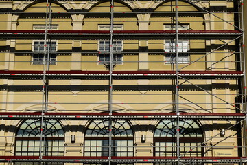 steel pipe scaffold structure with braces. silver gray metal color tubes and work stage. stucco facade renovation. construction and architecture concept. windows and arches. classic architecture.