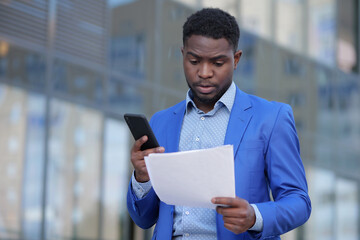 African American businessman examines monthly paper report of business. Black entrepreneur...