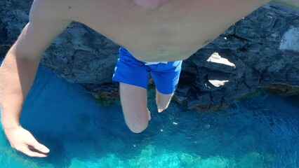 POV Extreme young man cliff jumping into ocean
