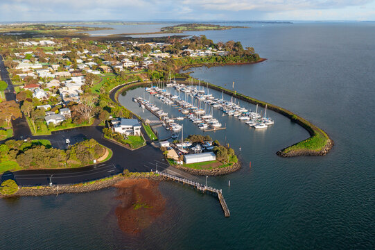 Aerial view of boats and yachts anchored in a sheltered marina surrounded by a breakwater