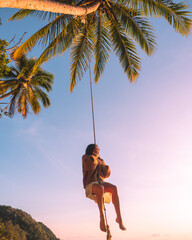 Woman swinging on rope swing. Palm tree paradise. 