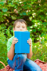 
Cute boy in a green t-shirt with a school backpack and school books in the park. Back to school