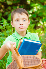 
Cute boy in a green t-shirt with a school backpack and school books in the park. Back to school