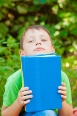 
Cute boy in a green t-shirt with a school backpack and school books in the park. Back to school