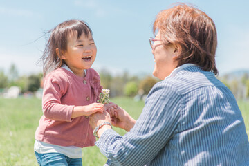 おばあちゃんに花を渡す子供（幼児・笑顔）
