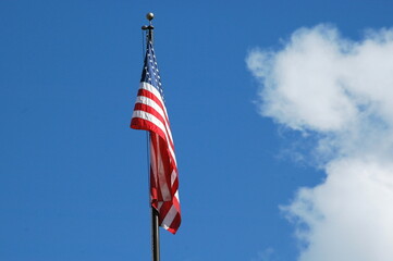 American flag flying high in the sky outdoors.