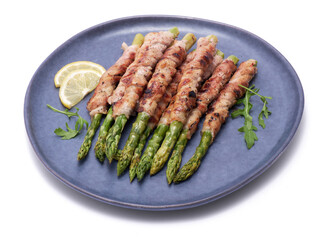 Healthy food - Asparagus wrapped with bacon and spices on a plate isolated on white background
