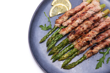 Healthy food - Asparagus wrapped with bacon and spices on a plate isolated on white background