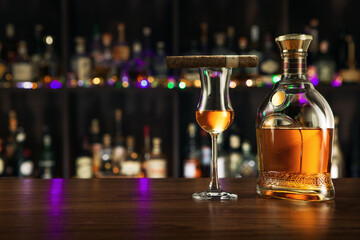 close up view of cigar, bottle of rum and glass aside on color back. 