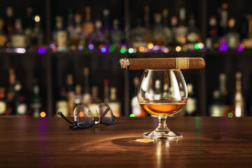 close up view of cigar and glass of whiskey on color back. 