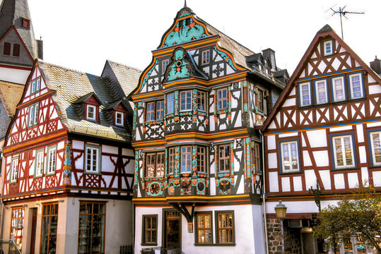 Die bunten Fassaden von drei in einer Reihe stehenden Fachwerkh&auml;usern in der historischen Altstadt von Idstein im Taunus, Hessen