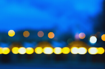 Abstract blurred background of defocused city lights at night. Colorful glowing bokeh of street lighting against a dark blue night sky. Space for copy text or design. - 526436764