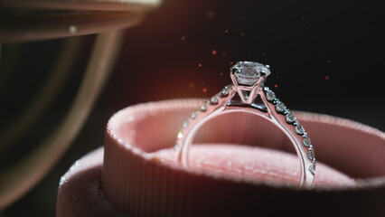 Close up of diamond ring in ring box with white flower, sunlight and shadow background. Love,...